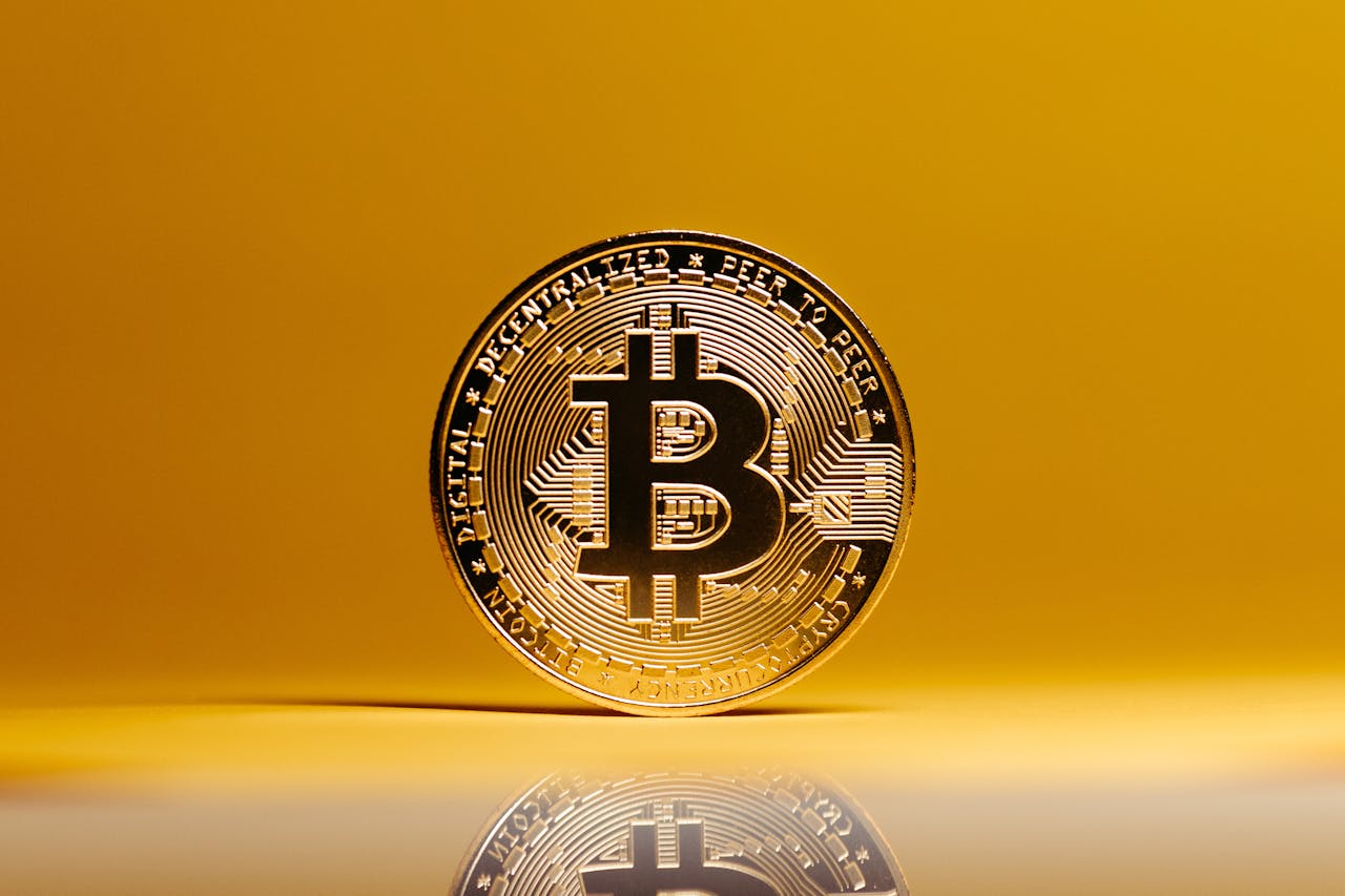 Golden Bitcoin coin showcased against a vibrant yellow background, symbolizing digital currency.